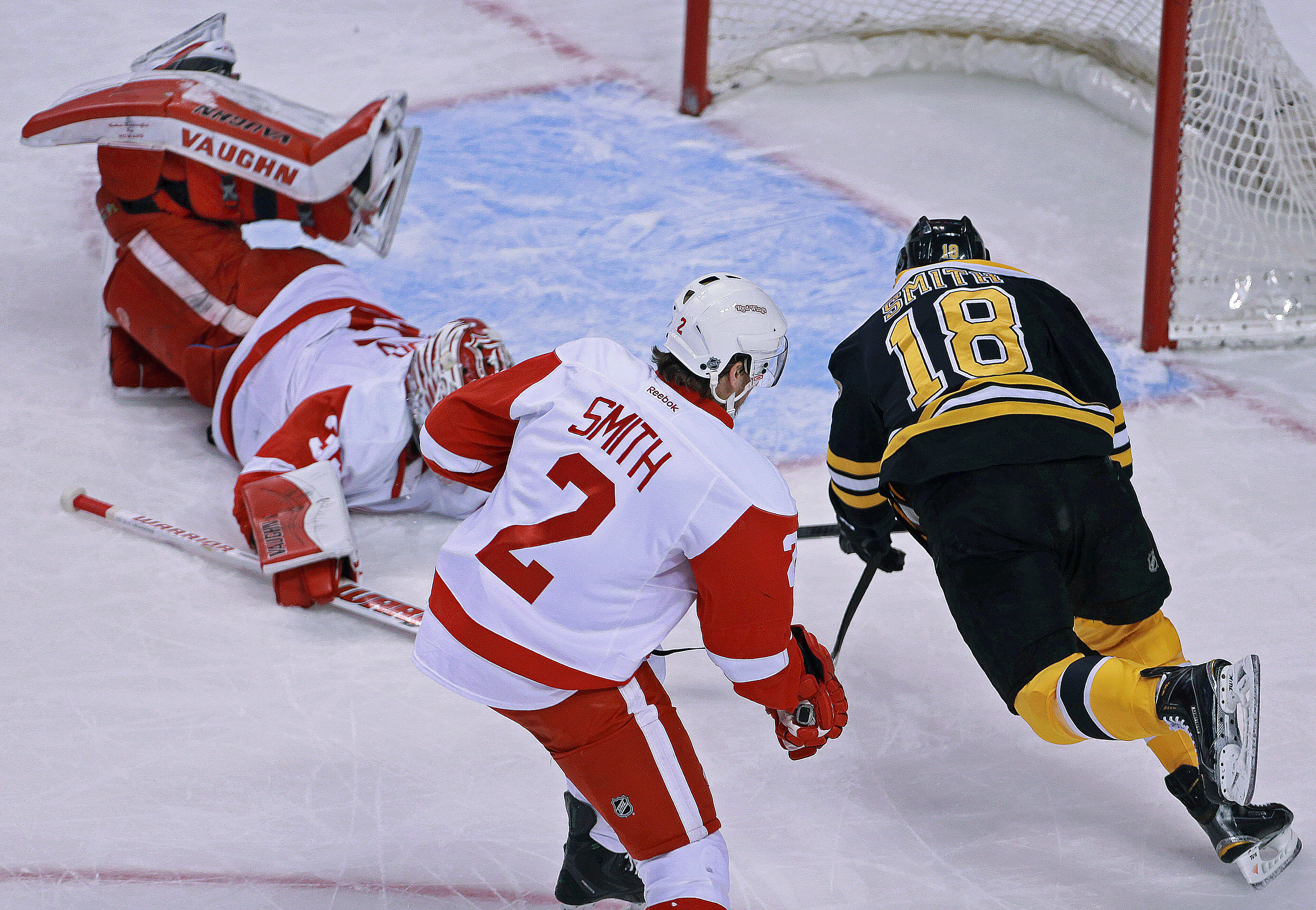 BOSTON - DECEMBER 29: Red Wings goalie Jimmy Howard dives out to stop a first period scoring bid by the Bruins Reilly Smith. right, with Smith's brother Brendan, center, helping out on defense. The Boston Bruins hosted the Detroit Red Wings in a regular season NHL game at the TD Garden. (Photo by Jim Davis/The Boston Globe via Getty Images)